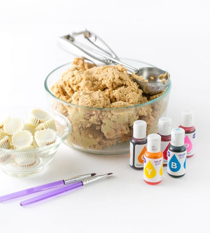 Ingredients for Watermelon Cookie Cups - peanut butter cookie dough, food coloring, food safe paint brushes, white peanut butter cups, and black food pen.