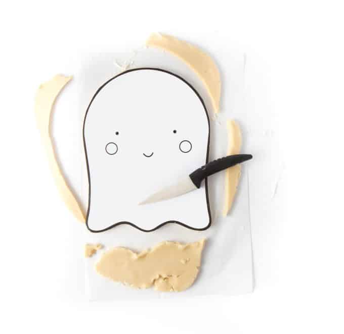 Cutting printable ghost cookie cake out of sugar cookie dough with knife