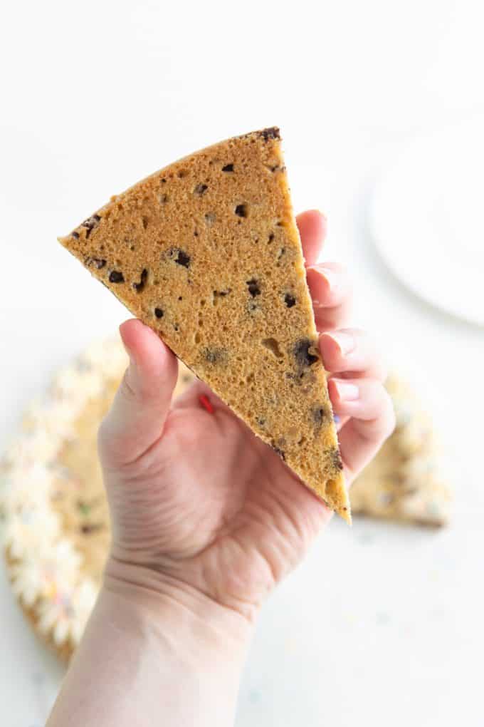 Hand holding piece of cookie cake upside down to show the smooth, durable texture