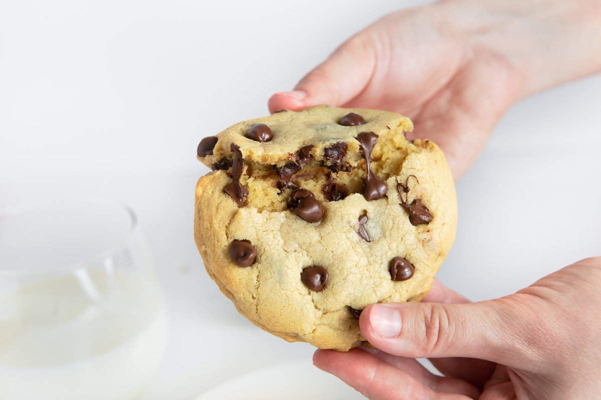 Hand breaking open melty & gooey chocolate chip cookie