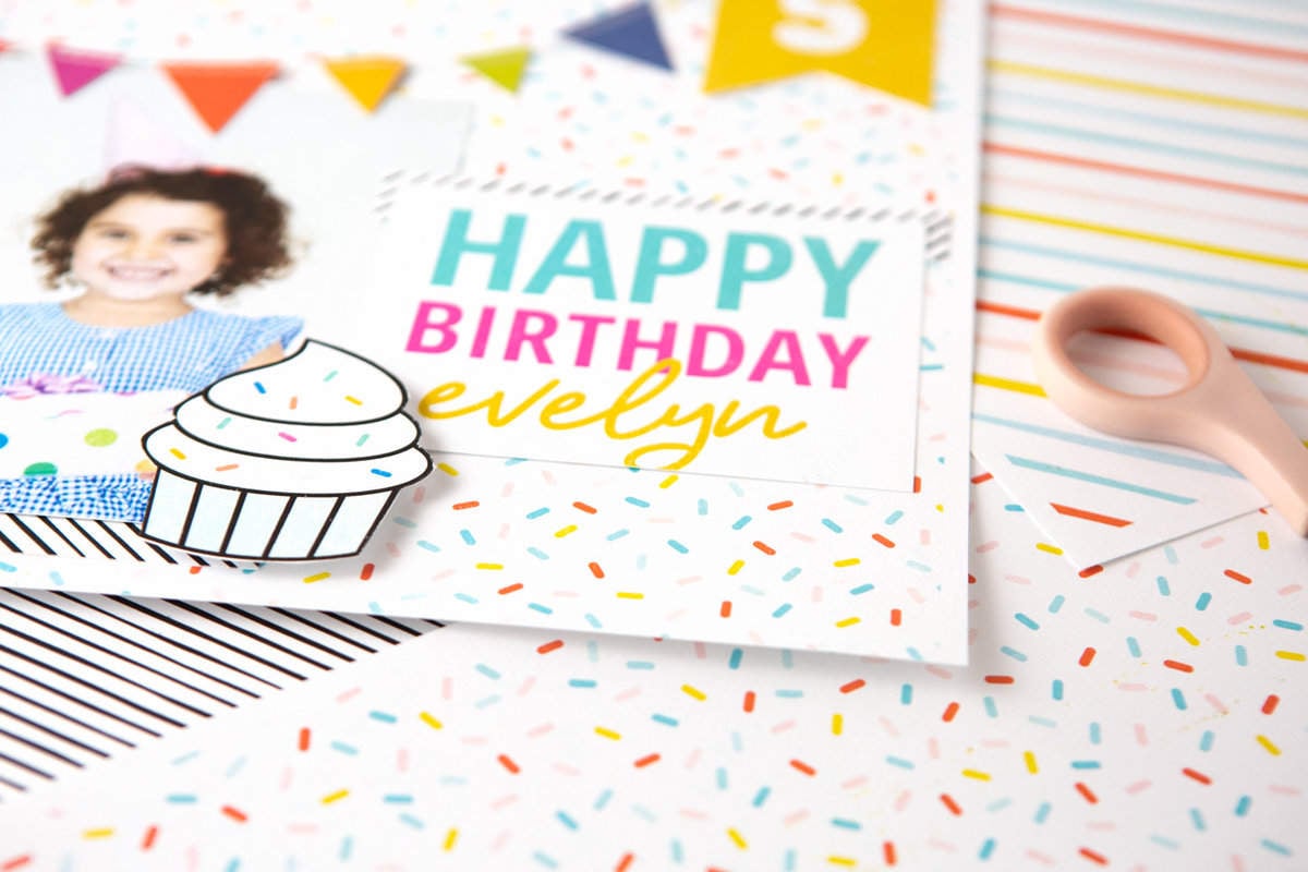 Colorful rainbow scrapbook page design with Happy Birthday text, cupcake, and banner