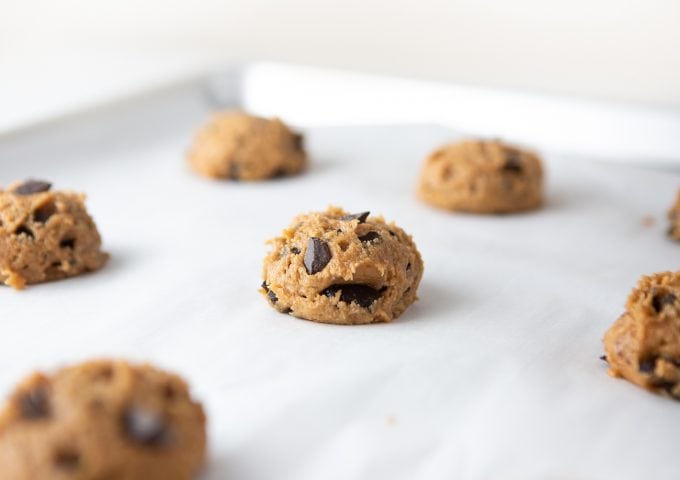 Raw dough scoops of peanut butter chocolate chip cookies on baking tray