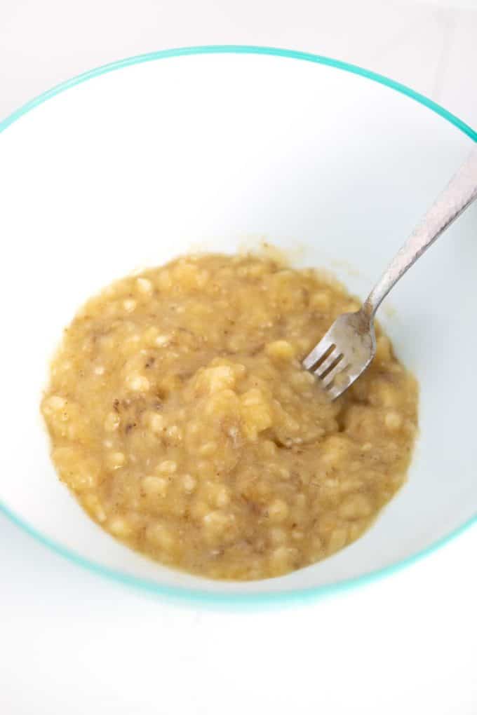 Mashing ripe bananas with fork in bowl