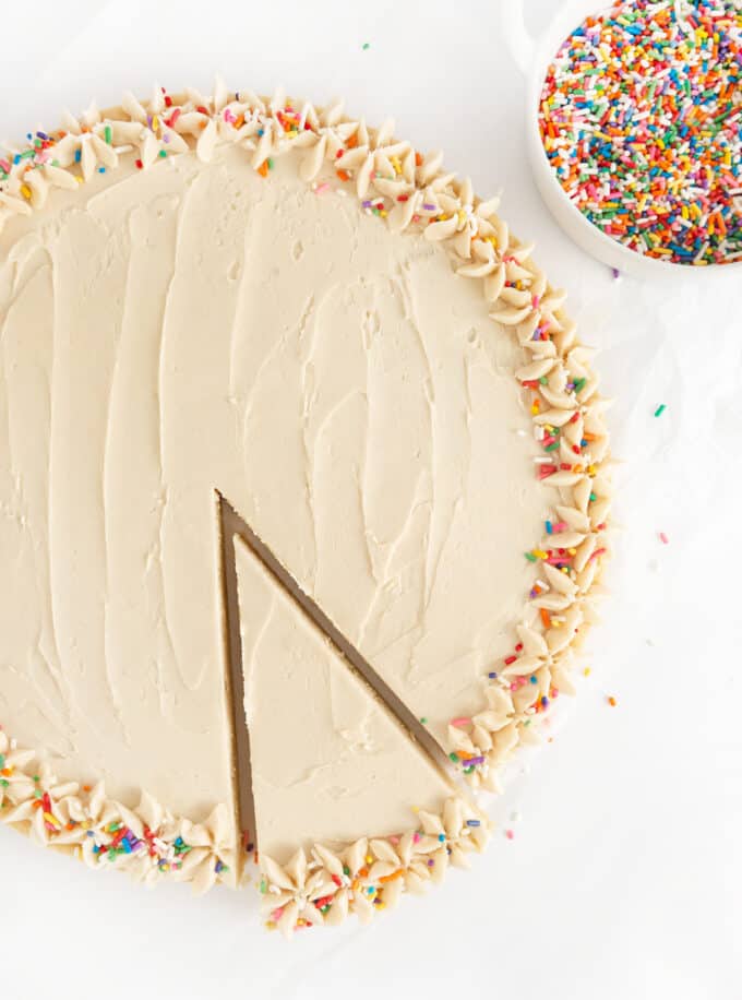 round sugar cookie cake with rainbow sprinkles and slice taken out