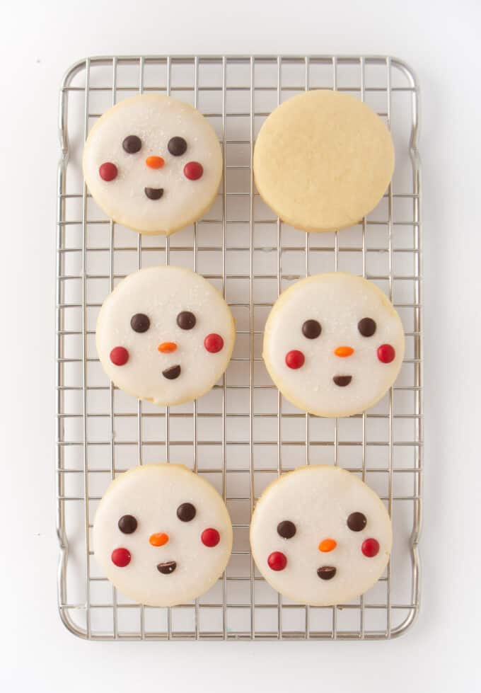 6 decorated snowman cookies on wire cooling rack