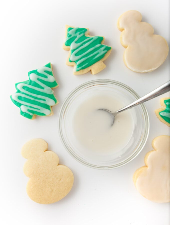 bowl of white icing and cut out christmas tree sugar cookies with green icing
