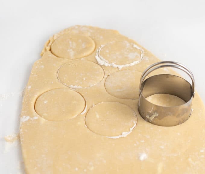 sugar cookie dough being cut with metal circle cookie cutter