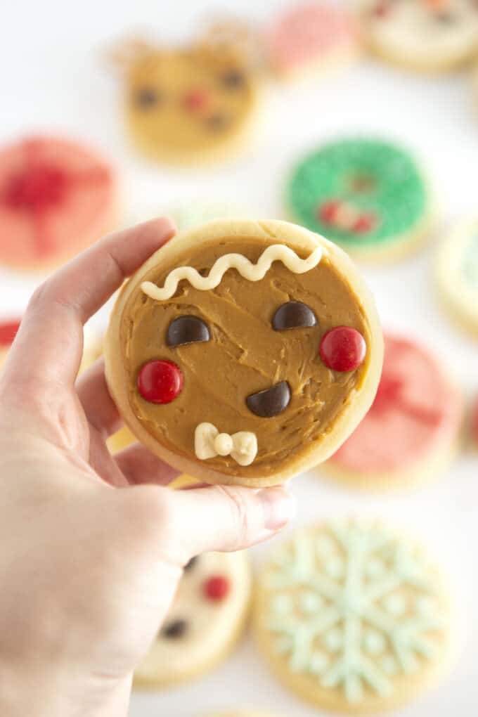 hand holding brown gingerbread man face cookie