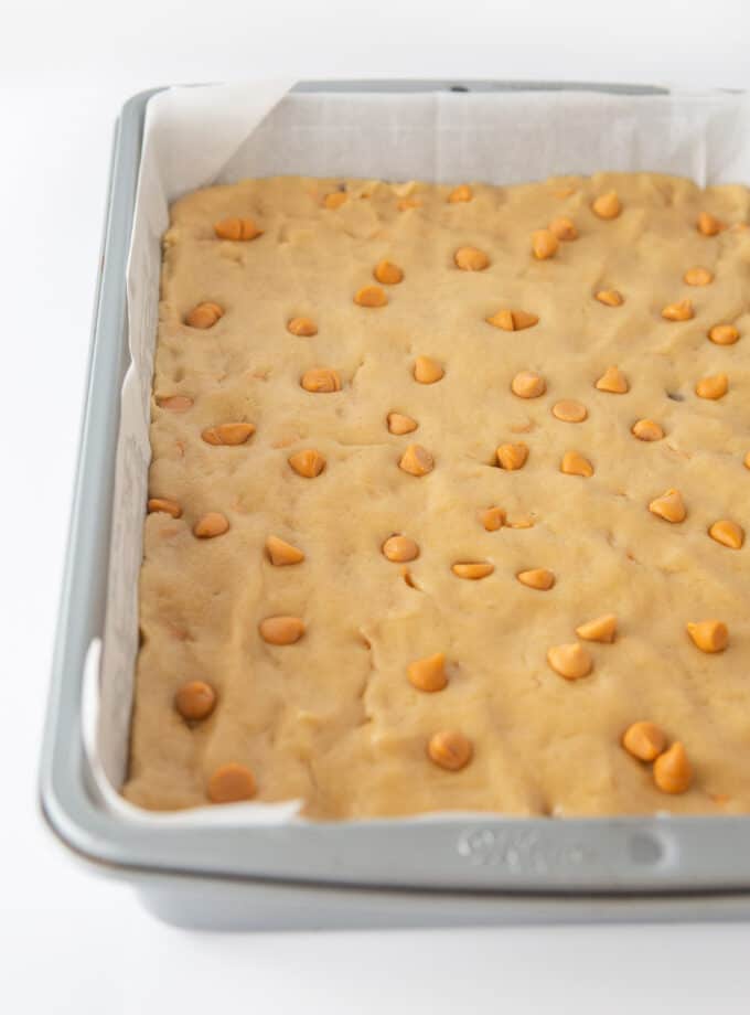 9x13 metal pan with butterscotch cookie dough pressed on parchment paper