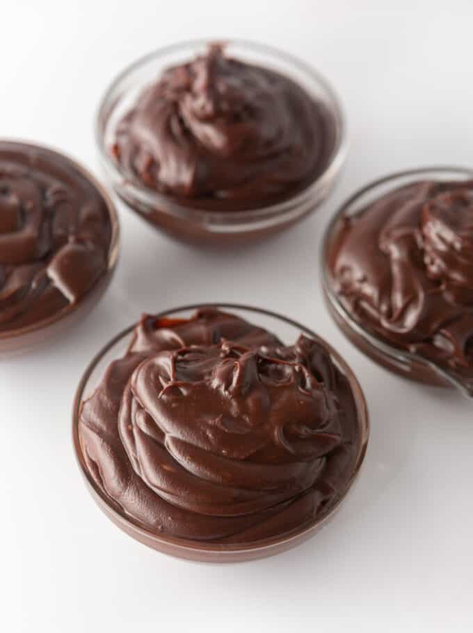Four small glass bowls filled with chocolate ganache made with milk