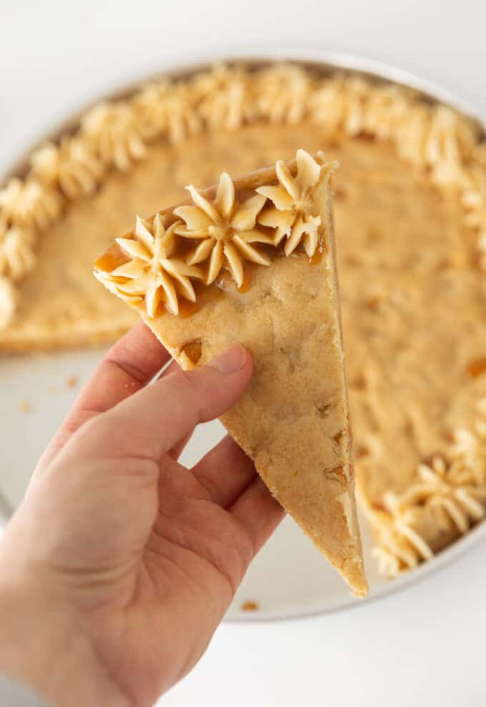 Hand holding a slice of butterscotch cookie cake