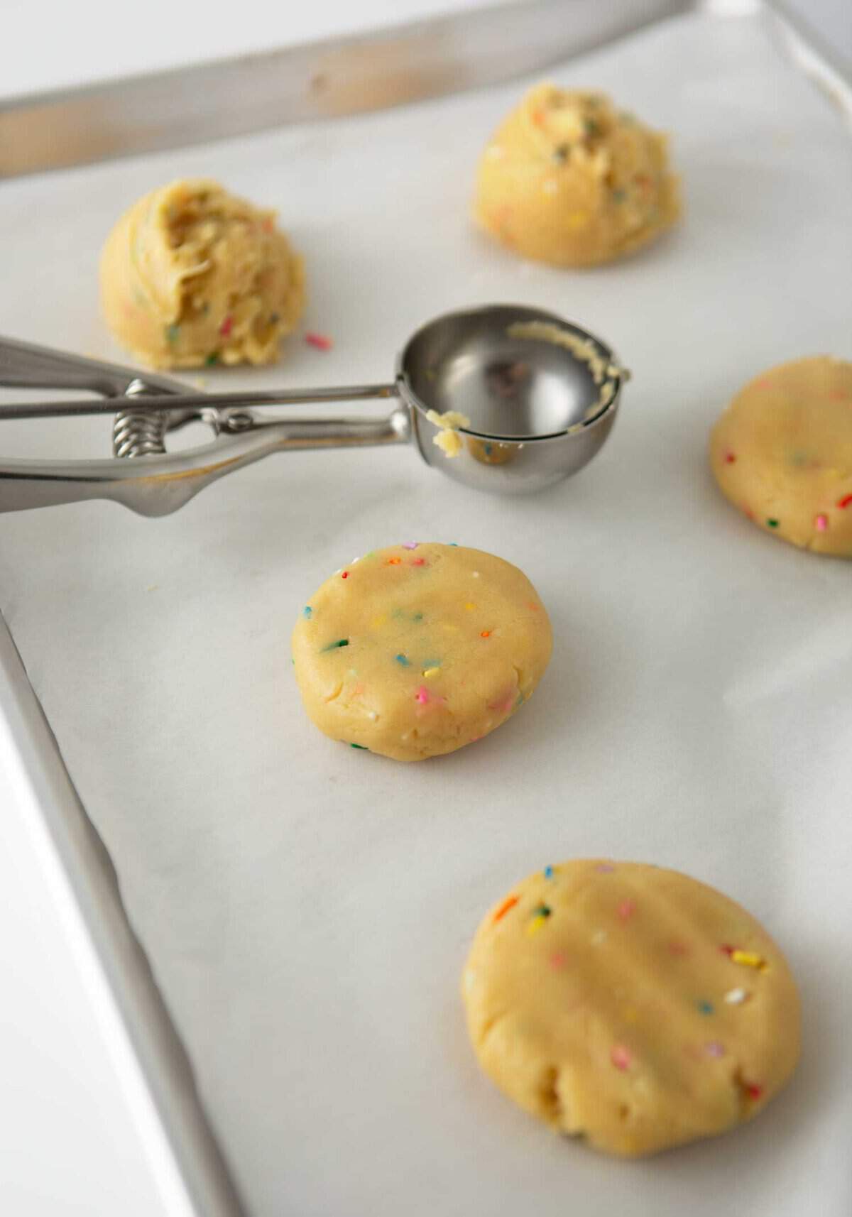 scooped cookie dough on pan with metal cookie scoop