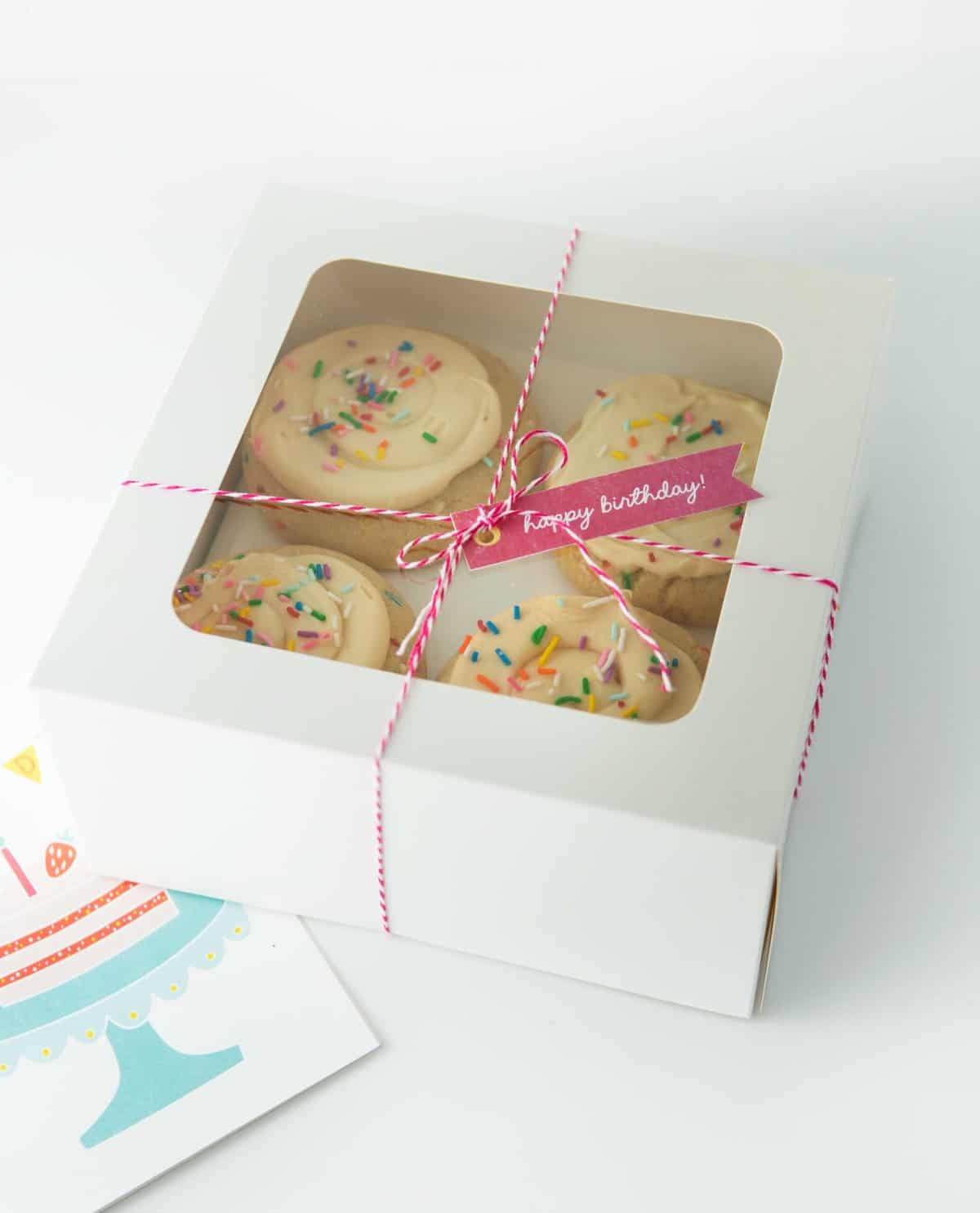 square white bakery box with window showing frosted sugar cookies