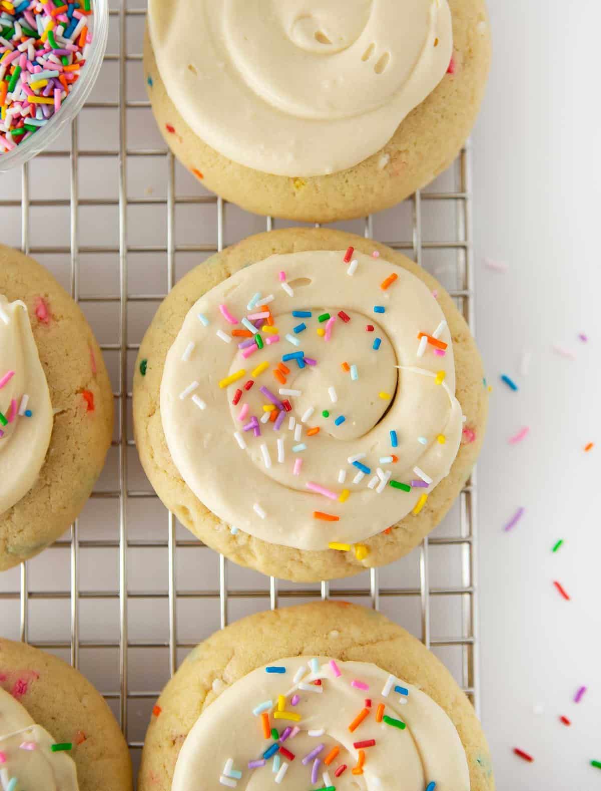 birthday cake cookies with frosting and sprinkles on wire cooling rack