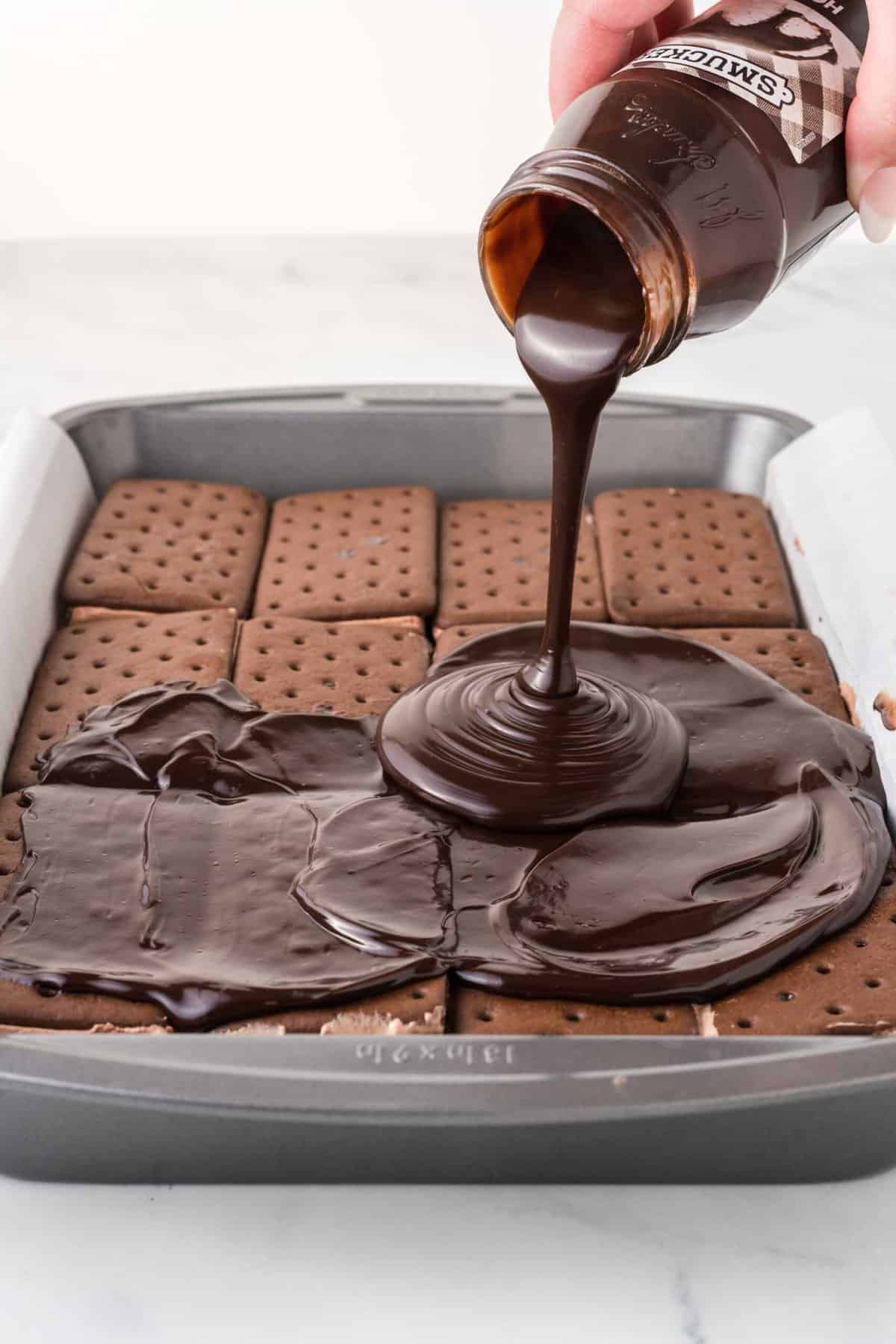 Pouring fudge sauce onto ice cream sandwich cake