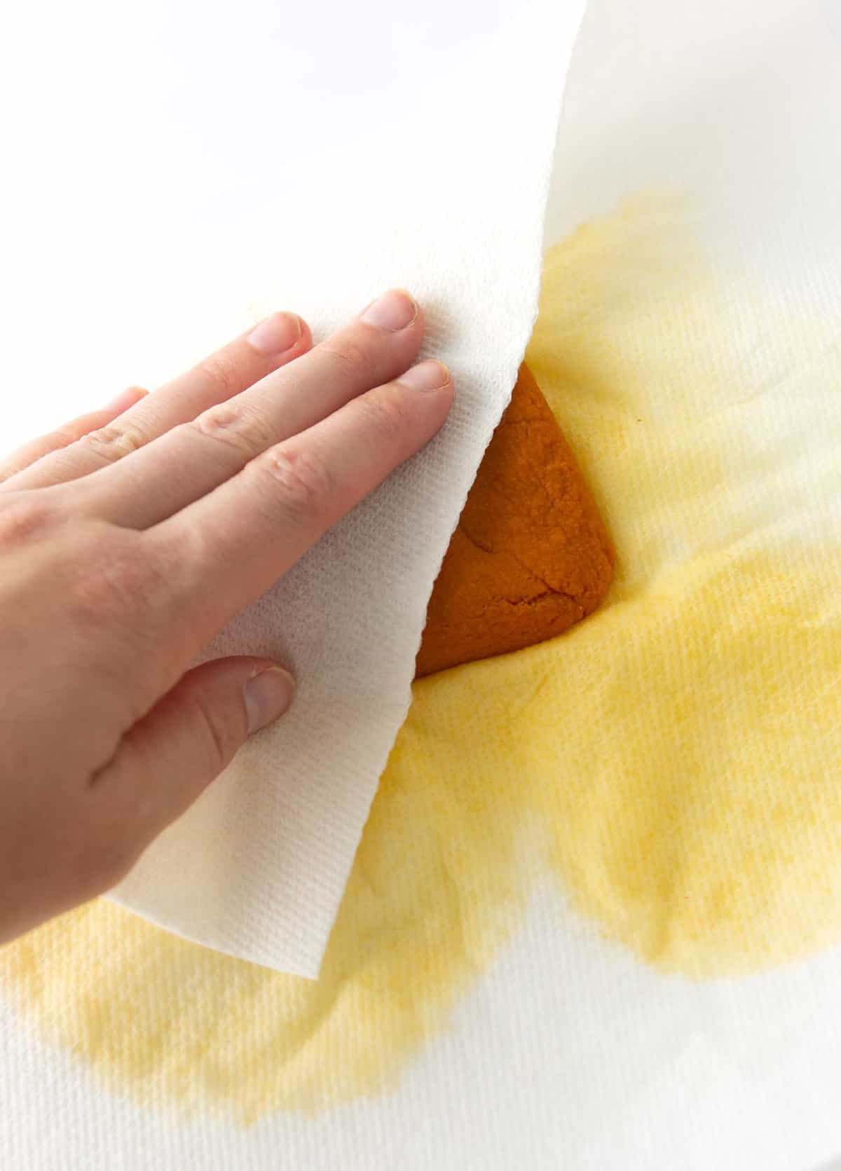 blotting water out of pumpkin puree with paper towel