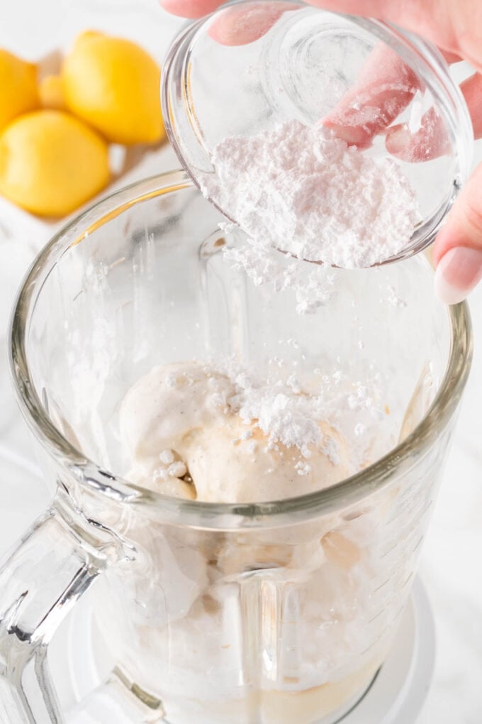 pouring powdered sugar in a blender to make frosted lemonade