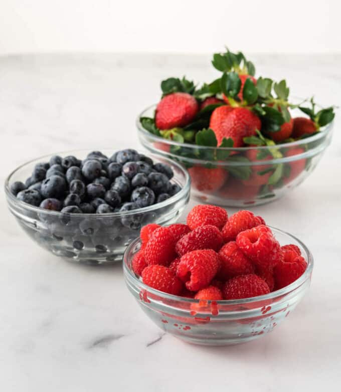 glass bowls of raspberries, blueberries, and strawberries