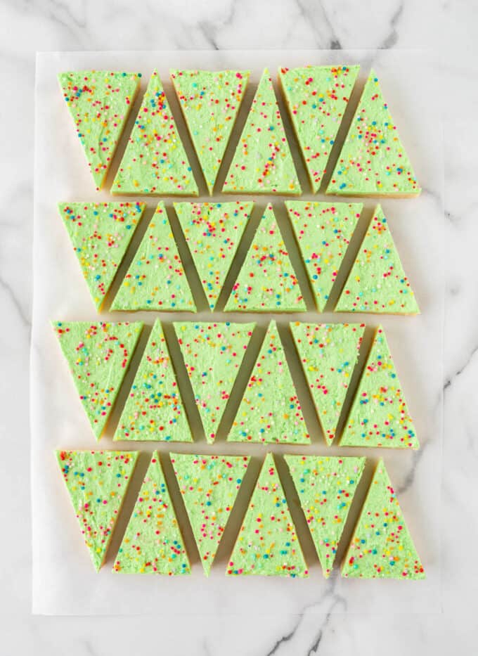 hand holding green christmas tree sugar cookie bars with nonpareil sprinkles baked in 9x13 pan