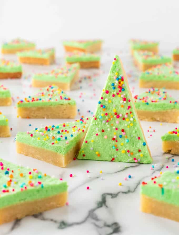 hand holding green christmas tree sugar cookie bars with nonpareil sprinkles