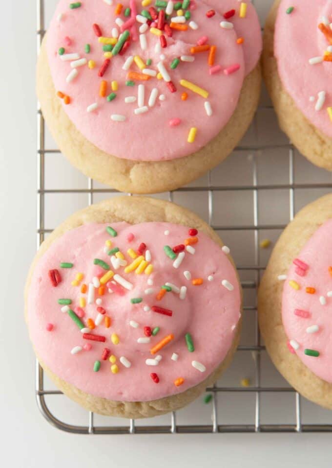 soft frosted sugar cookies on cooling rack with pink frosting and rainbow sprinkles