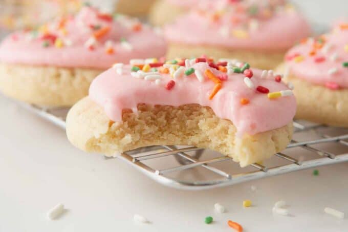 soft frosted sugar cookies with pink frosting and bite to show soft texture
