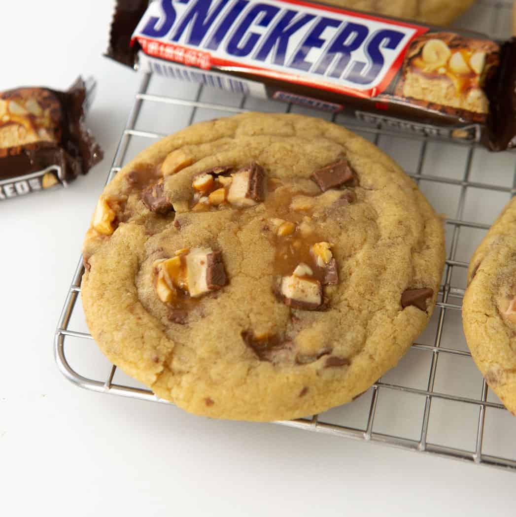 snickers cookies on wire cooling rack with candy bar