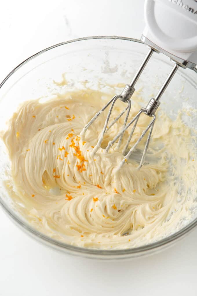 bowl of orange cream cheese frosting for cookies