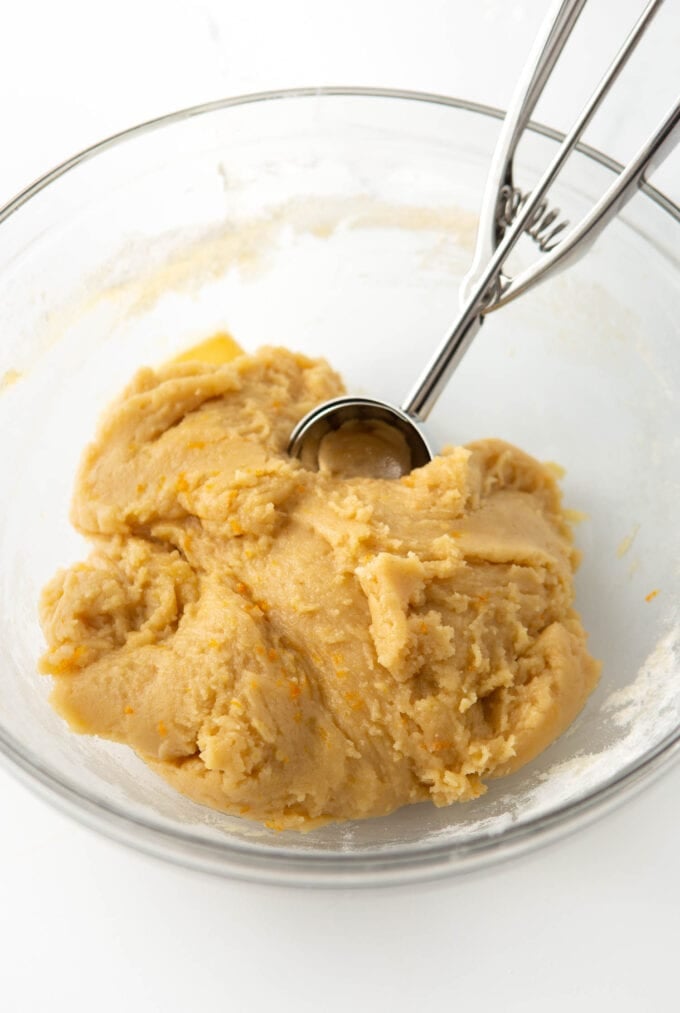 bowl of raw orange sugar cookie dough with cookie scoop