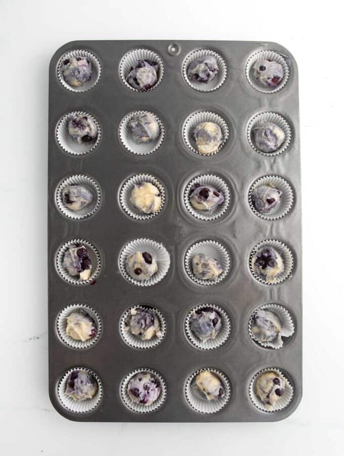 mini muffin tin filled with blueberry muffin batter