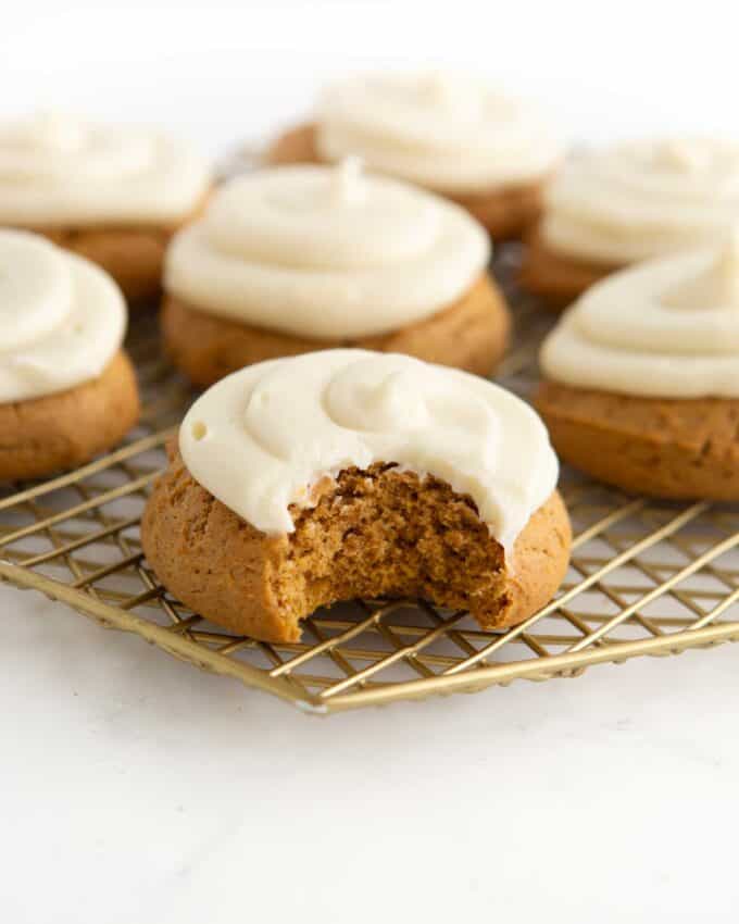 soft frosted pumpkin cookies on golden wire rack