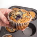 Hand holding jumbo blueberry muffin.