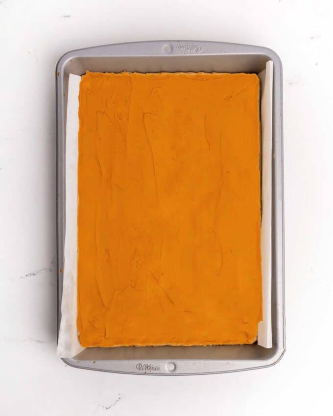 9x13 pan of sugar cookie bars with orange frosting