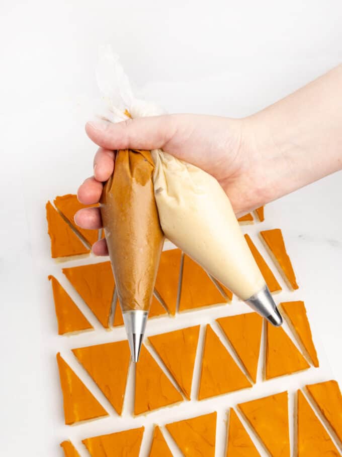 hand holding piping bags with brown frosting and white frosting