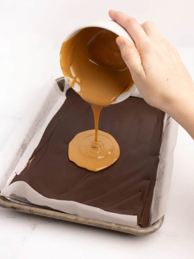 pouring melted peanut butter on chocolate bark