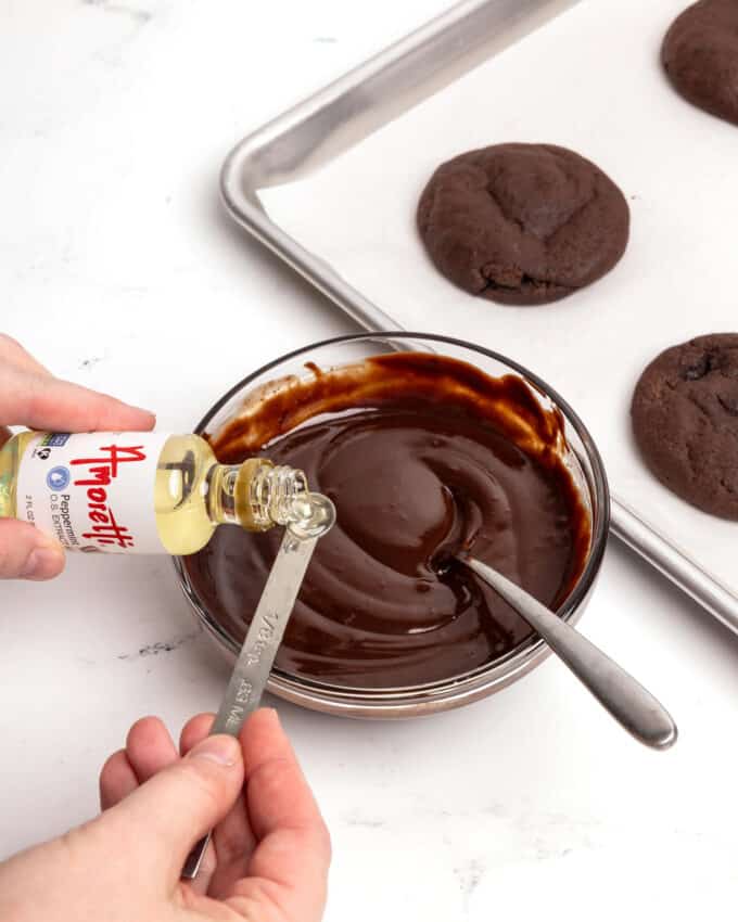 pouring peppermint extract into bowl of chocolate ganache