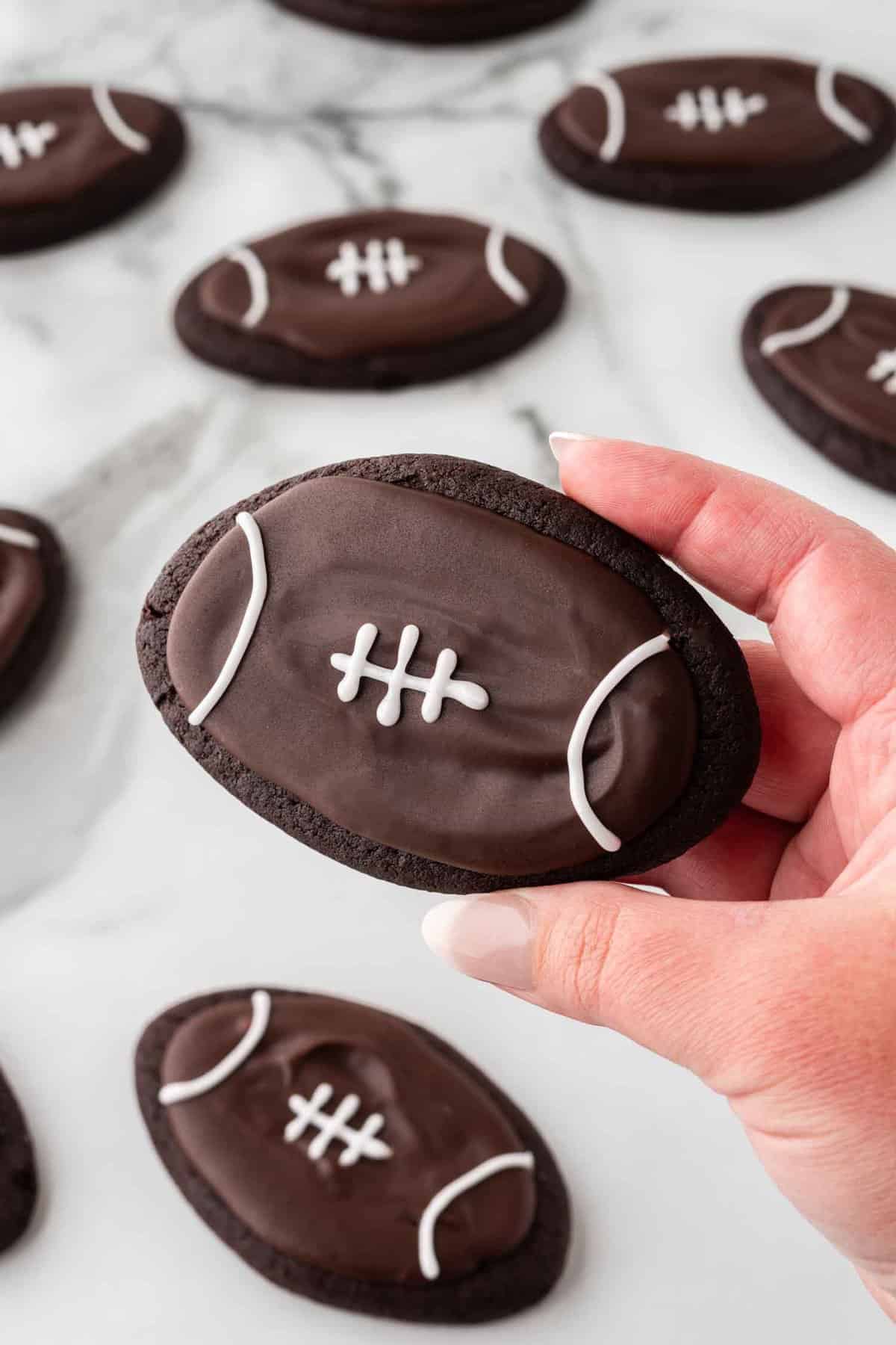 hand holding fudgy brownie cookies decorated as footballs