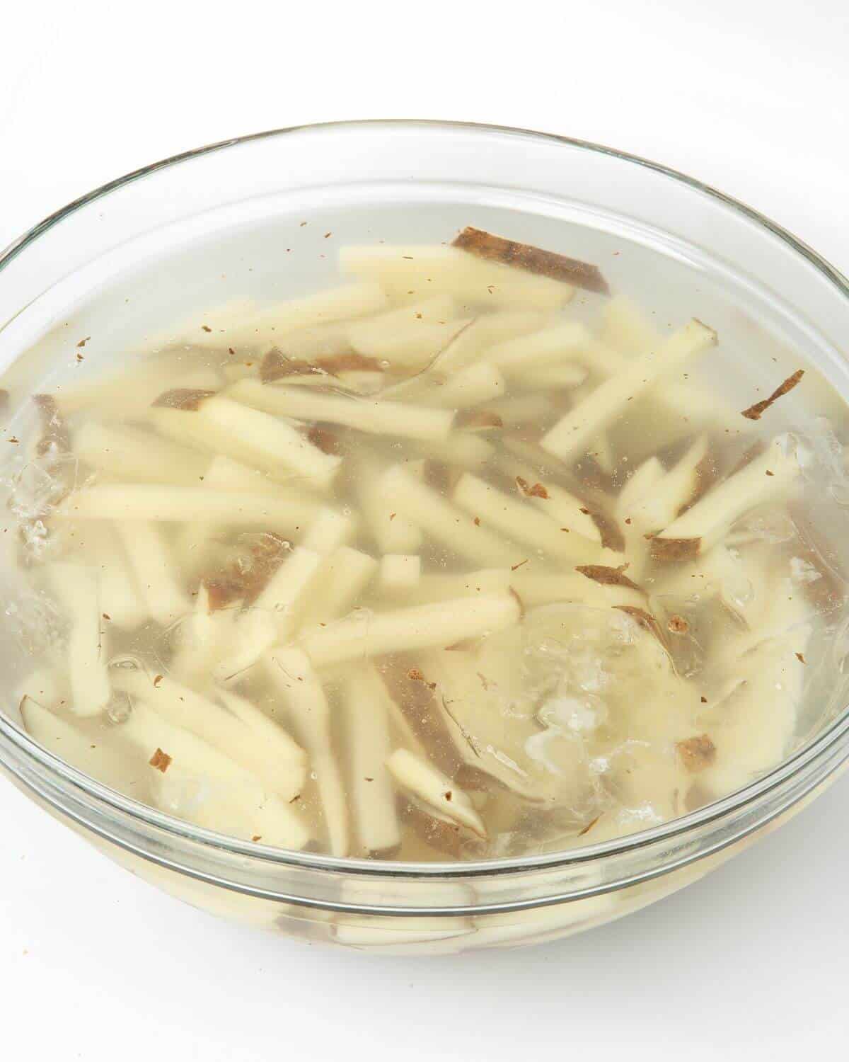 cut potatoes soaking in bowl of water