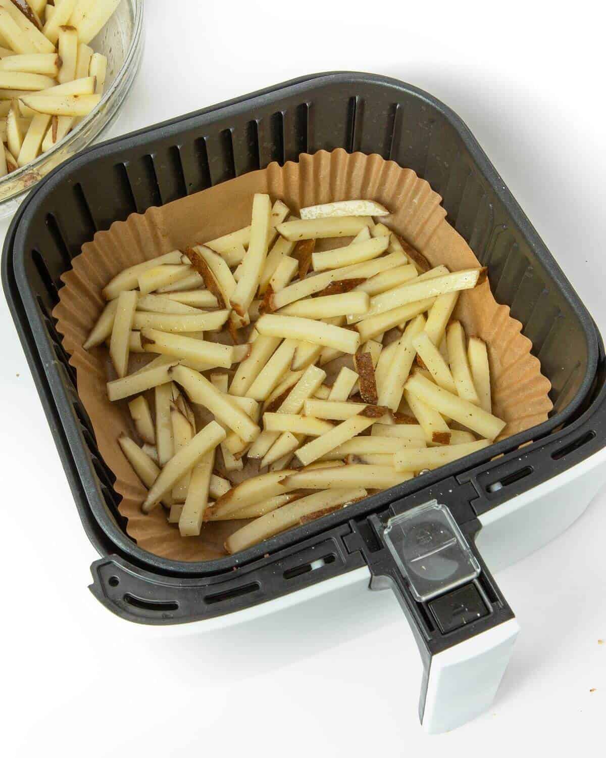 cut potatoes in air fryer tray with paper liner