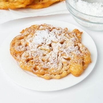 funnel cake with powdered sugar on white plate