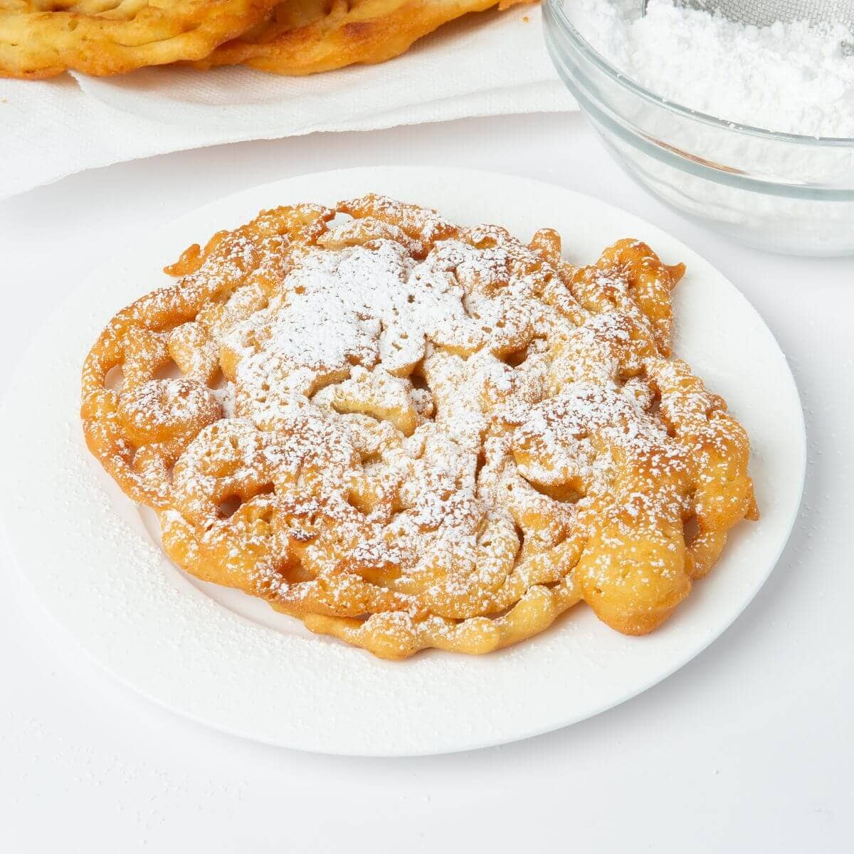 funnel cake with powdered sugar on white plate