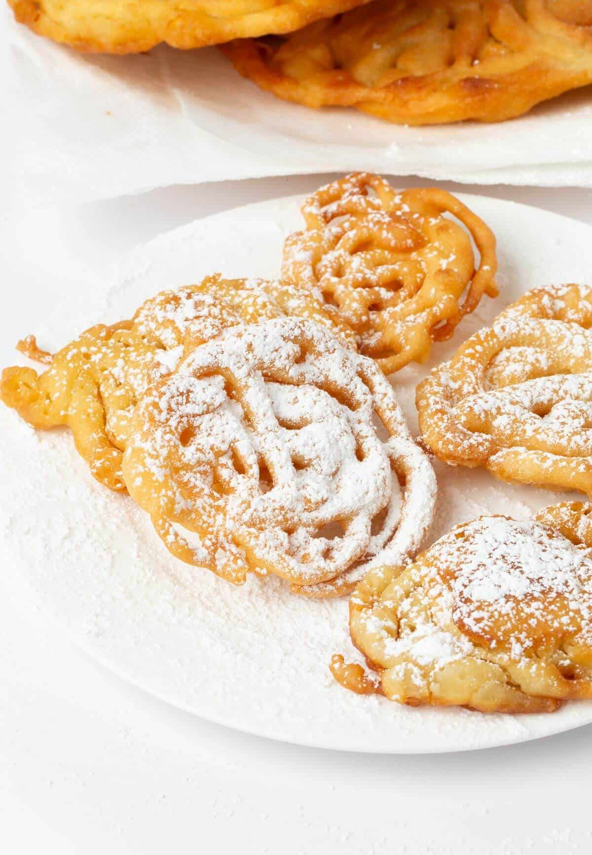 easy funnel cakes on white plate with powdered sugar
