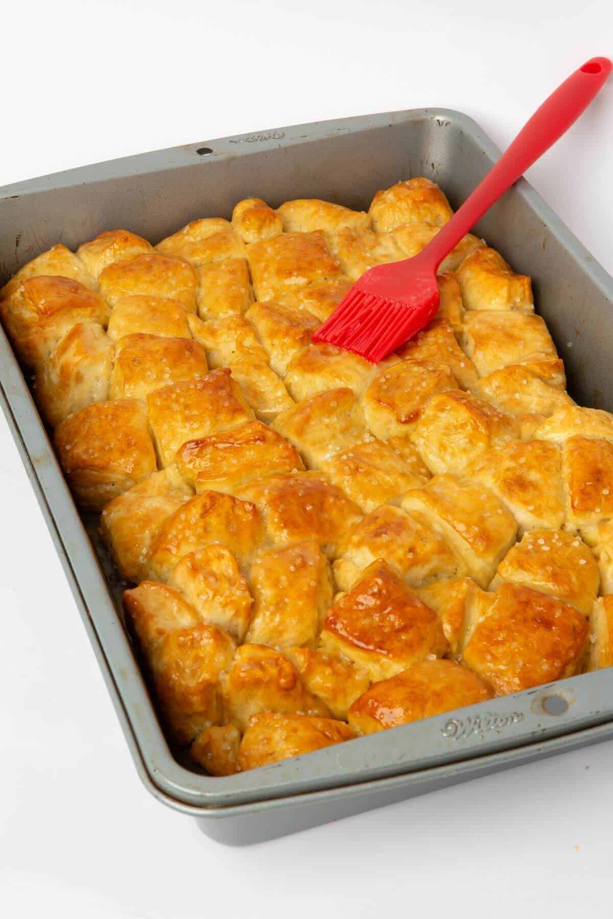 pretzel bite monkey bread baked in pan with silicone brush