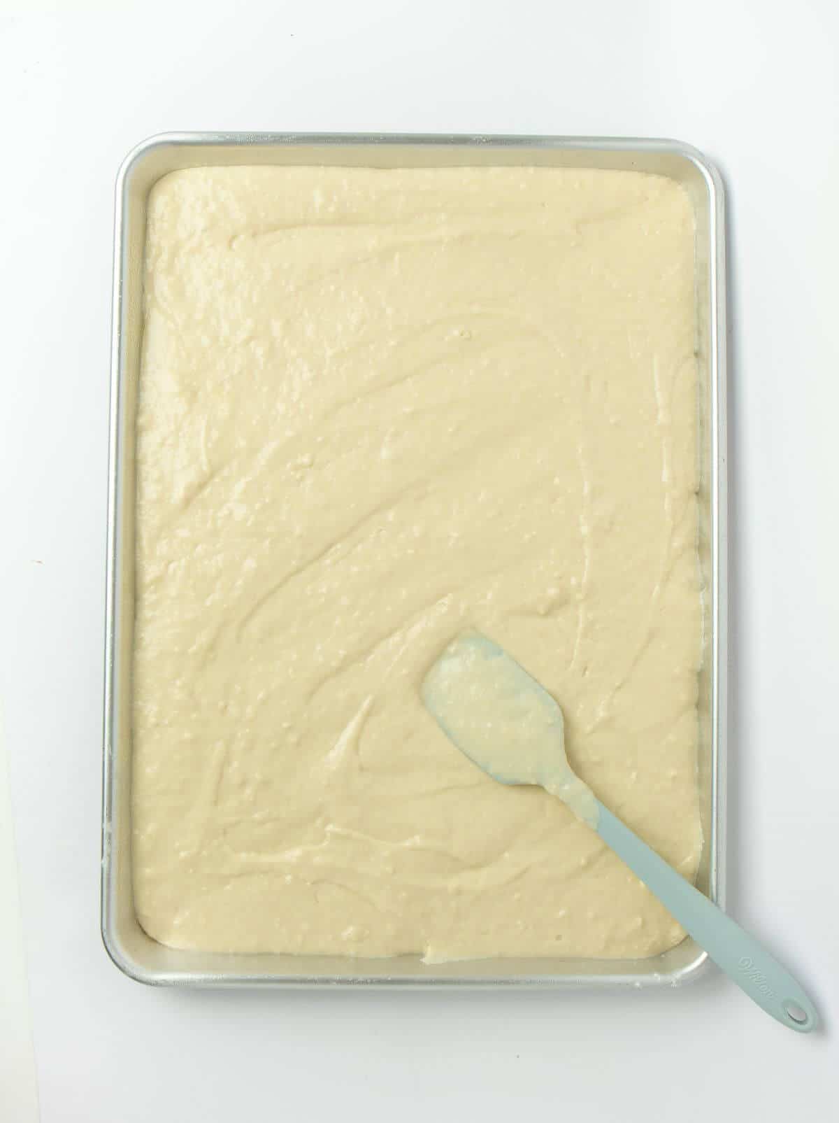 pancake batter on sheet pan spread with rubber spatula