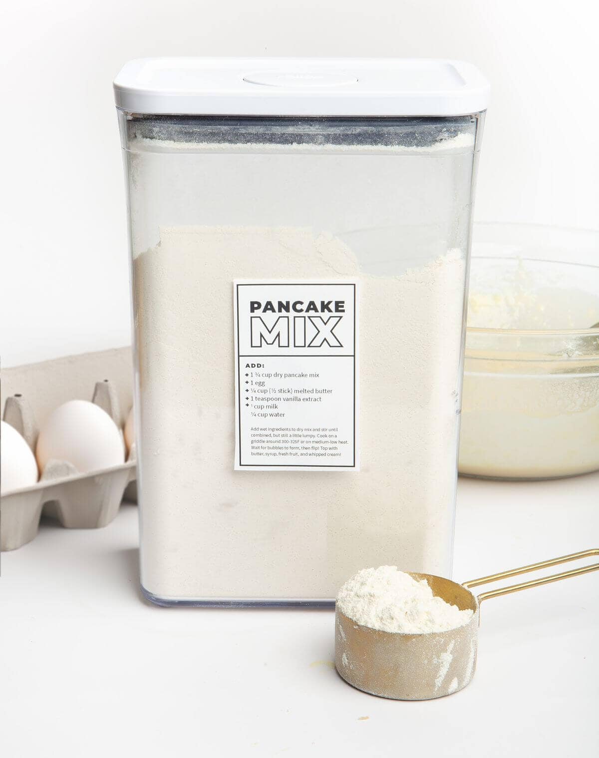 pancake mix in large container with measuring cup of mix