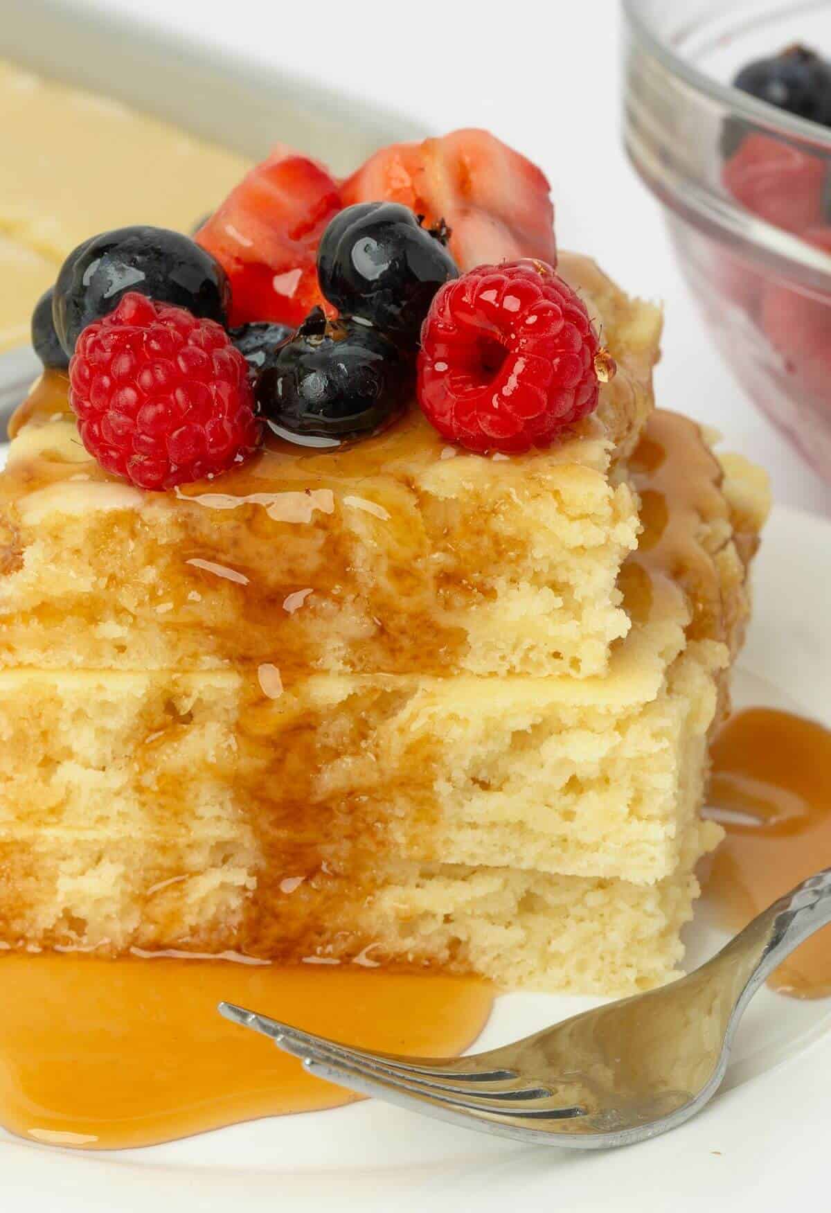 sheet pan pancakes topped with syrup and fruit on plate with fork