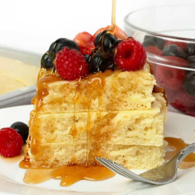 stack of three sheet pan pancakes on plate with fresh fruit and syrup on top