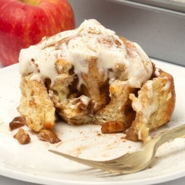 white plate with apple cinnamon rolls and apple in background