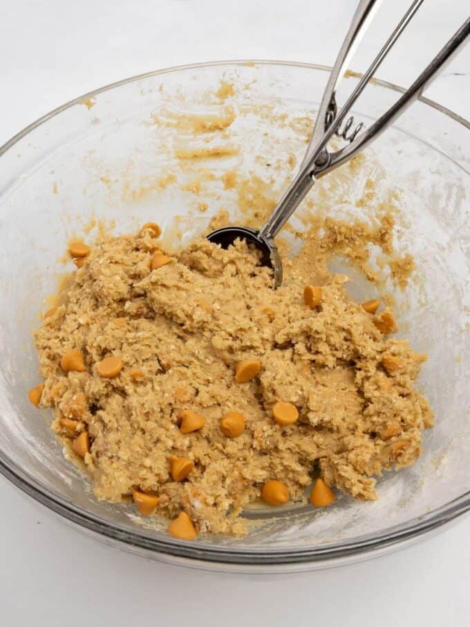 oatmeal scotchie cookie dough in glass mixing bowl with cookie scoop