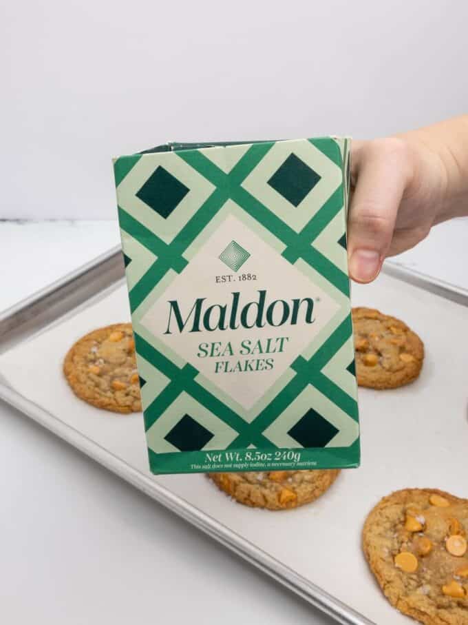 box of sea salt in front of oatmeal scotchie cookies on baking sheet